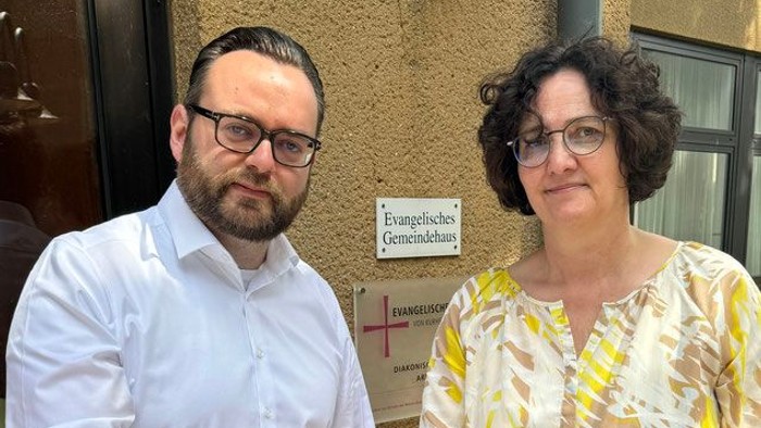 Mann und Frau halten einen großen Scheck.