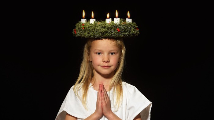 Et lille pige med en adventskranse på hovedet.