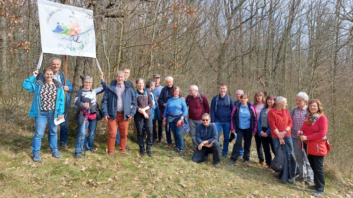 Eine Gruppe von Menschen posiert im Wald, eine Person hält ein Banner hoch