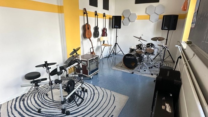 Ein Musikprobenraum mit Schlagzeug, Gitarren und Lautsprechern