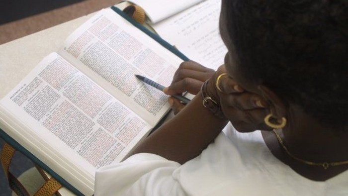 Person reading and writing in a book.