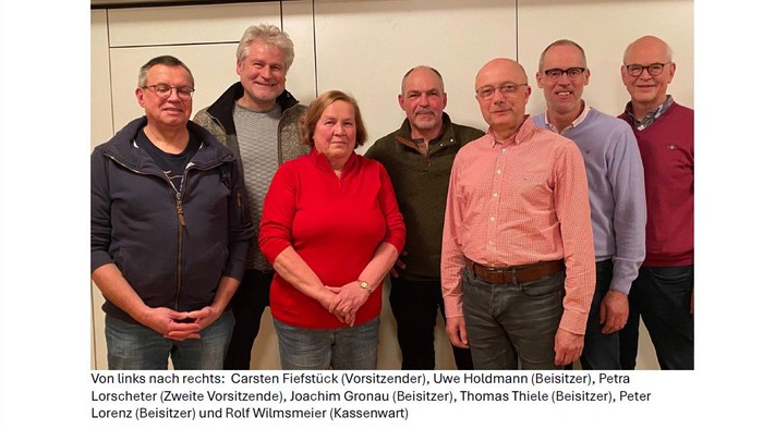 Ein Gruppenfoto von sieben Personen, die in einer Reihe stehen und in die Kamera lächeln.