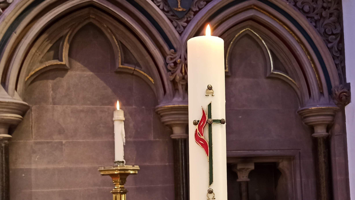 Zwei brennende Kerzen vor einem Altarraum in einer Kirche
