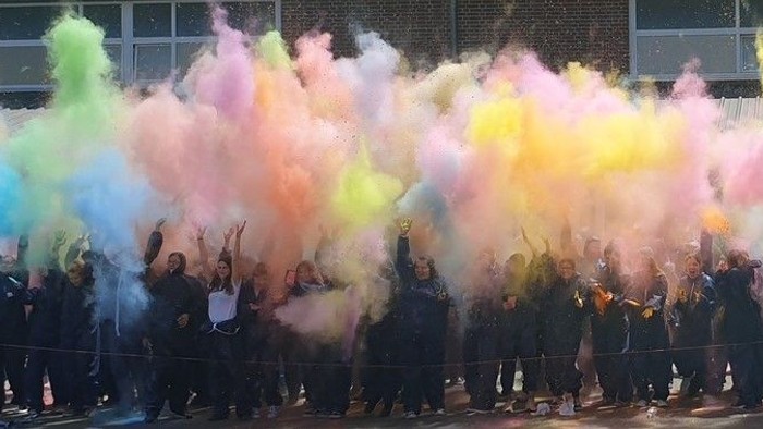 Eine Gruppe von Menschen wirft bunte Pulver in die Luft.