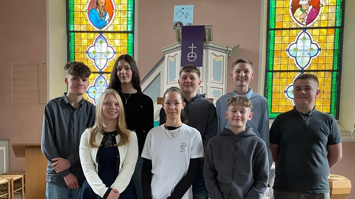Familie posiert in einer Kirche mit bunten Glasfenstern.
