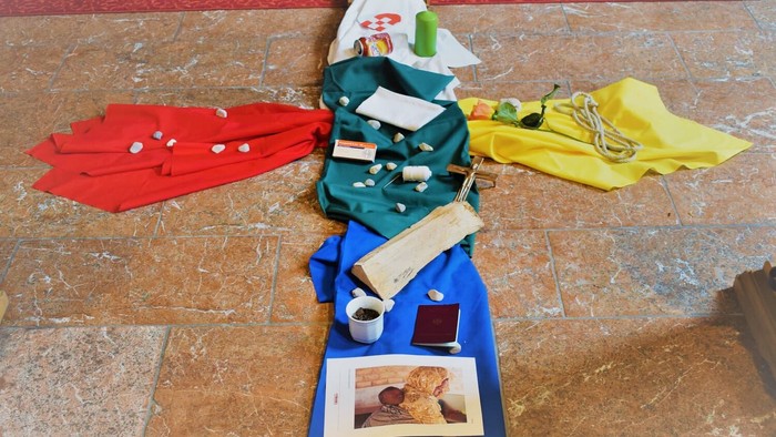 Überkreuz liegende farbenfrohe Kleidungsstücke und Accessoires auf einem Steinboden