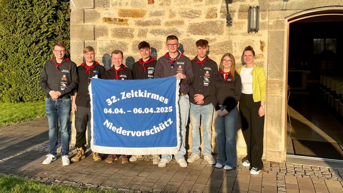 Gruppe von Menschen, die ein Transparent vor einem Steingebäude halten