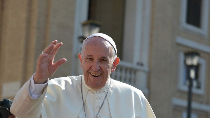 Papst Franziskus winkt und lächelt auf offener Fahrt