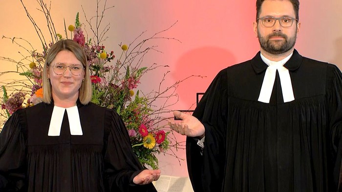 Zwei Personen in Richterroben halten Blumenstrauß