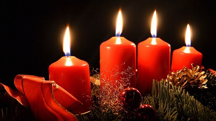 Vier brennende Kerzen in einem Adventskranz aus Tannenzweigen