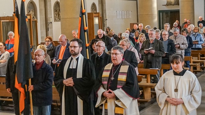 In der Kirche versammeln sich Menschen um Flaggen und Bücher.