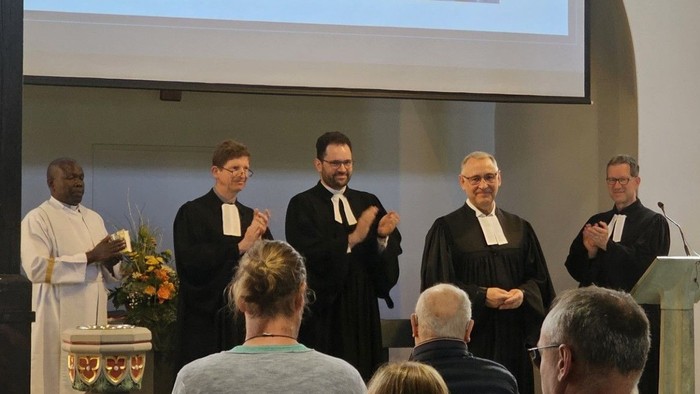 Ein Priester predigt in einer Kirche vor einer Gruppe von Gläubigen.