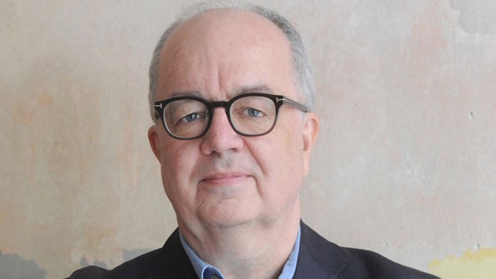 Mann, Mitte 60, Brille, Anzug, verschränkte Arme, freundlicher Blick nach vorne