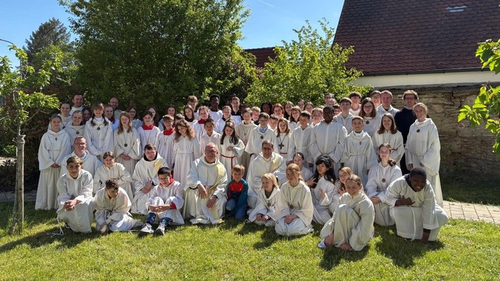 Eine Gruppe von Menschen in weißen Roben posiert im Freien vor einem Haus.