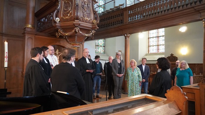 Eine Gruppe von Menschen steht in einem holzgetäfelten Raum und unterhält sich.
