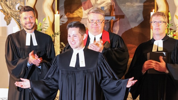 Vier Priester in Soutanen vor Altar