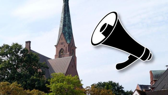 Ein Megafon schwebt vor einer Kirche mit hohem Turm und grünem Dach.