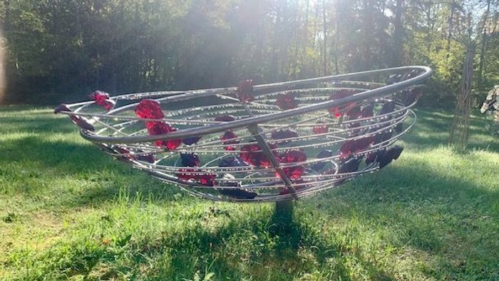 Drei rote und schwarze Kajaks liegen auf einem grasbewachsenen Feld.