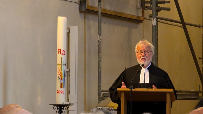 Ein Priester steht auf der Kanzel und hält einer Gemeinde in einer Kirche eine Predigt.