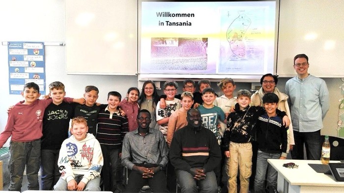 Eine Gruppe von Schülern und Lehrern posiert vor einer Präsentation über Tansania