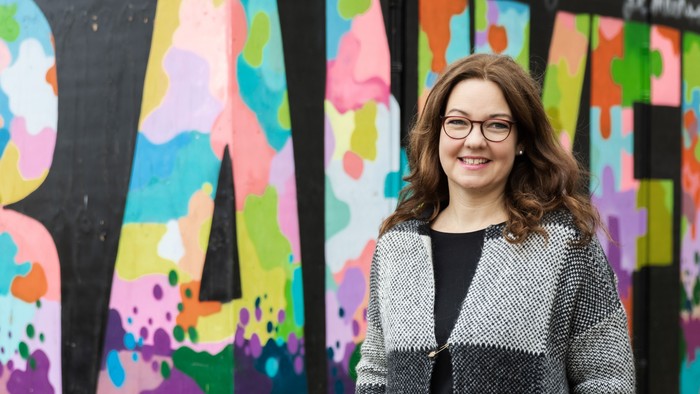 Frau vor buntem Graffiti-Mural mit dem Wort