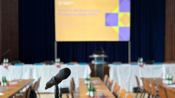 Ein Konferenzraum mit einem großen Bildschirm und Mikrofonen auf den Tischen