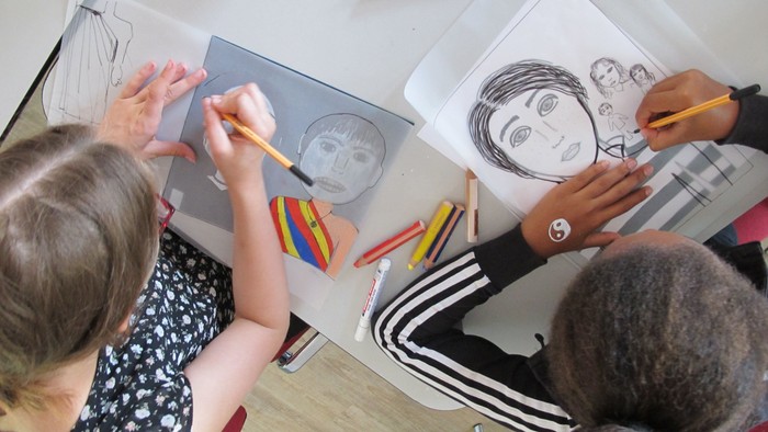 Zwei Kinder sitzen an einem Tisch und zeichnen.