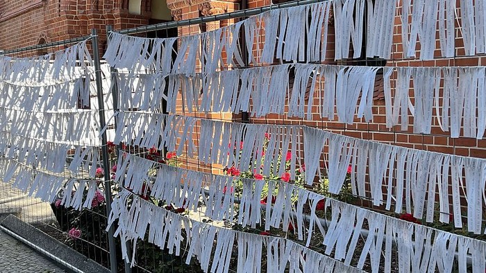 Weiße Stoffstreifen hängen an einem Ziegelgebäude
