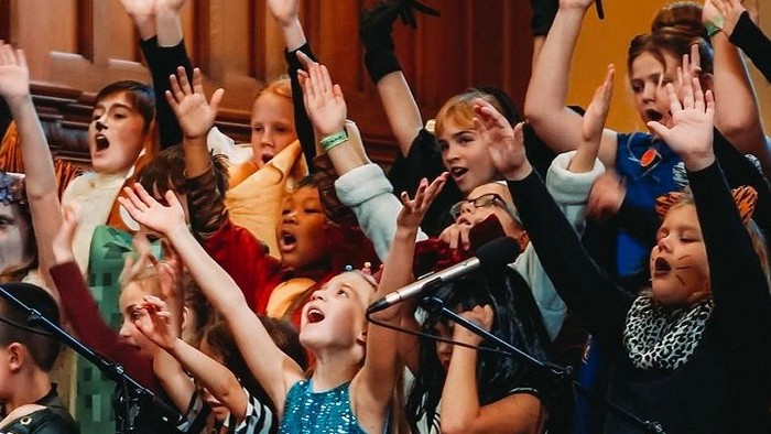En gruppe af unge kvinder synger med glæde og begejstring i en sangkor.