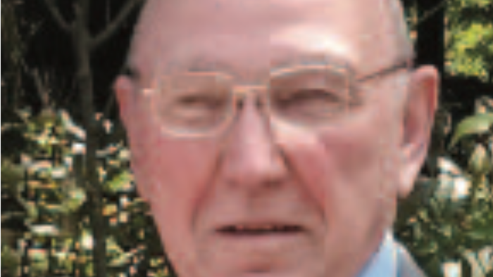 Ein älterer Mann mit Glatze und Brille im Freien.