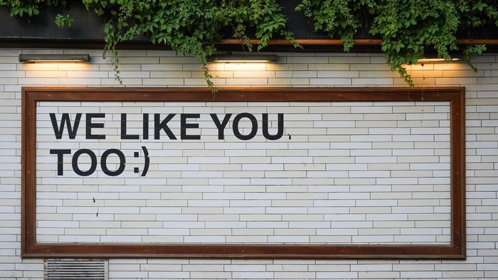 Das Schild an der Wand lautet "Wir mögen dich, zu sehr".