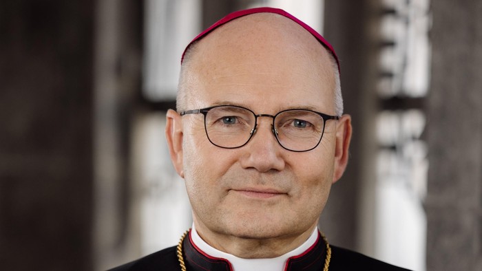 Ein Mann in kirchlicher Kleidung mit Birett und Brille.