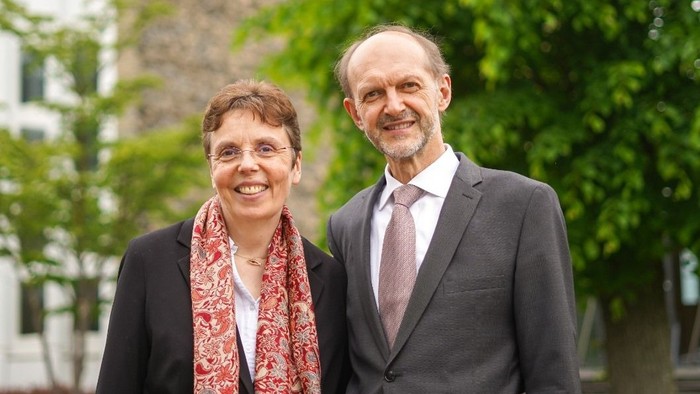 Ein Mann und eine Frau stehen lachend vor einem Baum