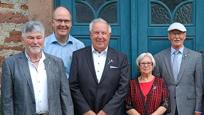 Fünf Personen stehen lächelnd vor einer grünen Tür.