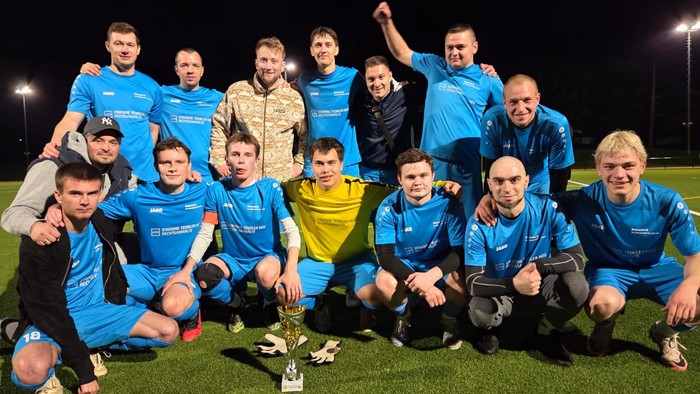 Ein Fußballteam feiert den Sieg mit einem Pokal auf dem Feld