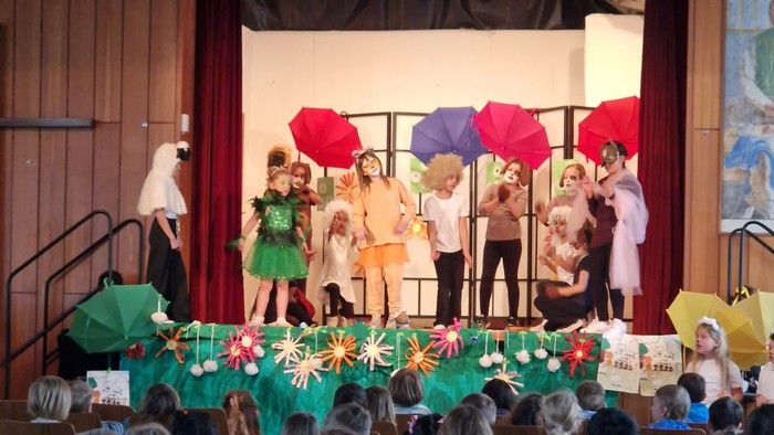 Kinder sitzen in einem Saal und schauen sich eine Theateraufführung an.