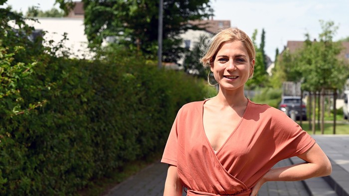 Eine junge Frau in einem orangefarbenen Kleid posiert im Freien.