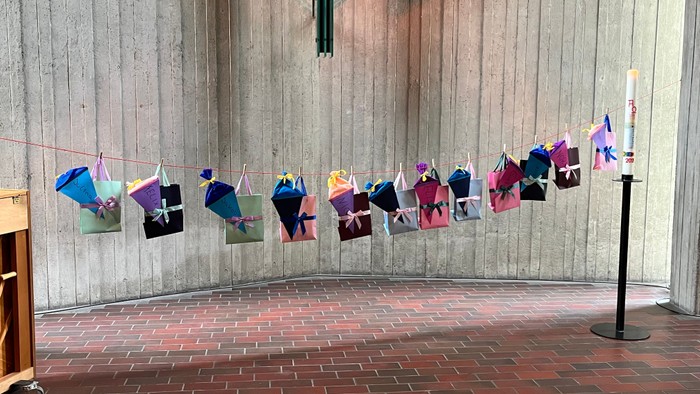 In der Kirche an einer Leine hängende bunte Tüten mit Namen