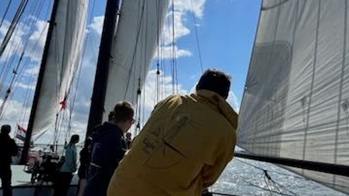 Mann auf Segelschiff mit großen Segeln und Sonnenschein