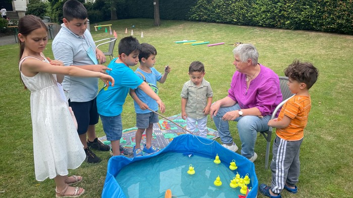 Mehrere Kinder stehen an einem Planschbecken und angeln gelbe Entchen.