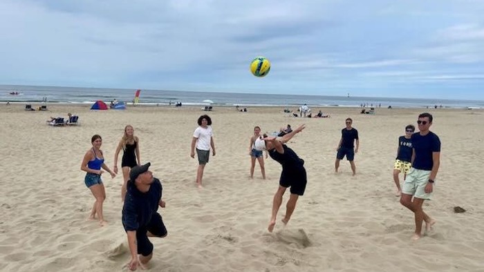 Ein Gruppe von Menschen spielt Strandfußball am Meer.