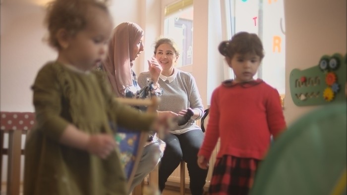 Einige Kinder spielen in einem hellen Raum mit einer Frau.