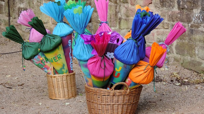 Bunte Schultüten in Körben vor Mauer