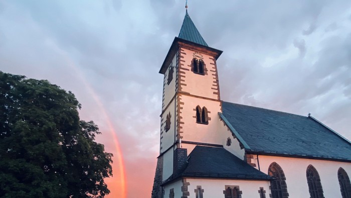 Kirchengebäude bei Sonnenuntergang mit Regenbogen