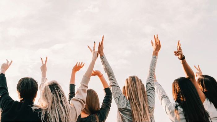Gruppe Jugendlicher von hinten zu sehen ehebt begeistert die Arme