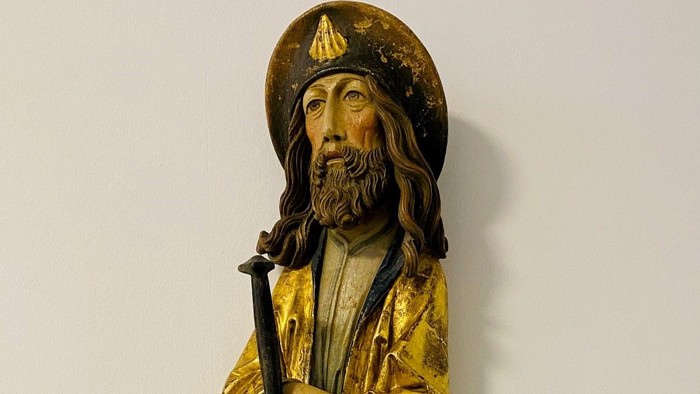 Die Statue zeigt einen bärtigen Mann in goldener Robe mit Stab.