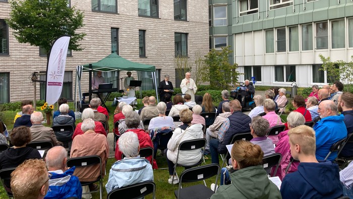 Auf dem Foto sieht man die Gemeinde im Vordergrund, Im Hintergrund unter einem Pavillon stehen die Musiker, rechts Pfarrerin Andrea Klausmann und Pastoralreferent Thomas Jakob.