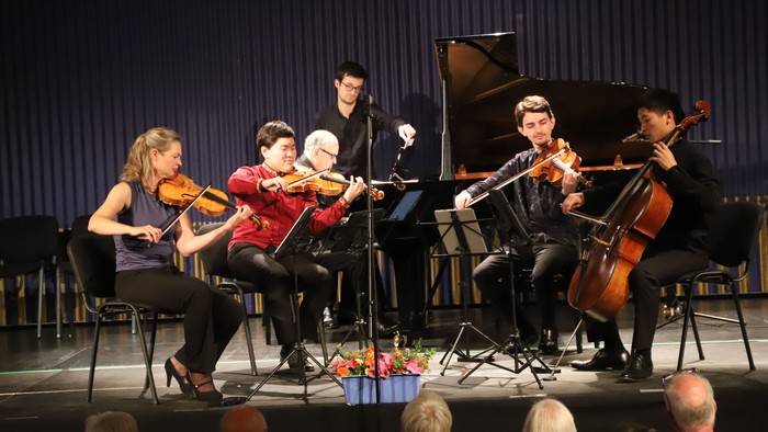 En gruppe musikere optræder på en scene med violin, cello og piano