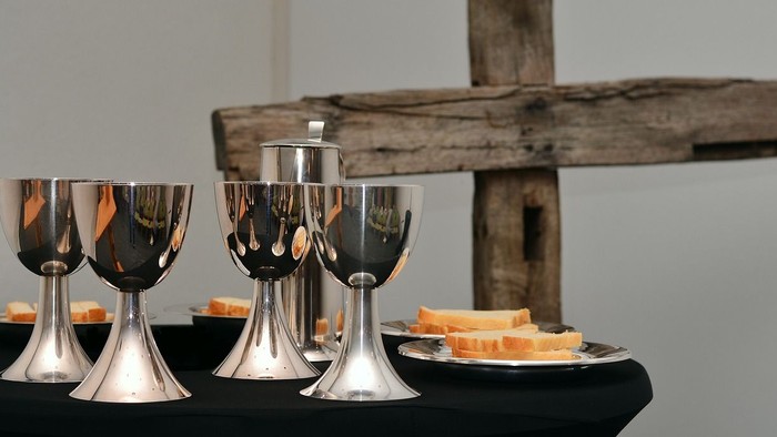 Silberne Weingläser und Käse auf schwarzem Tisch vor Holz.