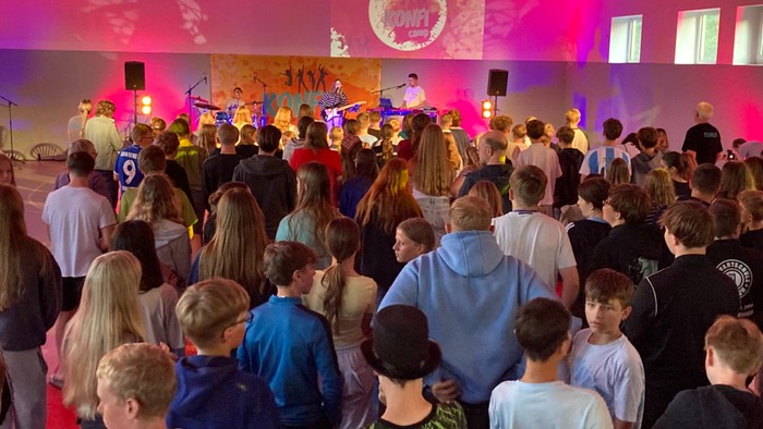 Eine Gruppe von Kindern tanzt auf einer Party mit einer Band im Hintergrund.